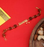 Customized Rudraksha name Rakhi bracelet with natural Rudraksha beads, gold-finish engraved name plate, and adjustable chain.