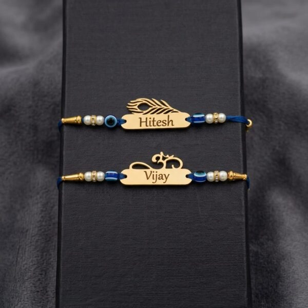 Customized gold name Rakhi with evil eye beads, pearl accents, silk thread, and engraved stainless steel name plate.