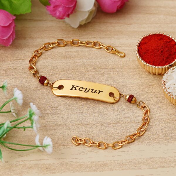Custom gold name bracelet Rakhi with Rudraksha beads, engraved name plate, and premium adjustable chain.