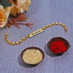 Elegant Skyline Chain Rakhi bracelet featuring a personalized engraved name plate in a premium gold finish.