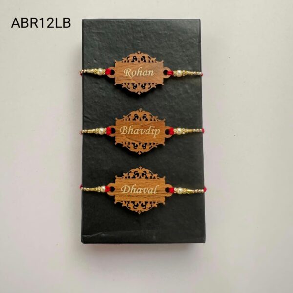 Personalized designer wooden name Rakhi with intricate laser-cut design, pearl bead accents, and traditional red thread for Raksha Bandhan.