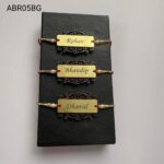 Custom engraved gold name Rakhi featuring an elegant ornamental base, premium pearl beads, and handcrafted festive red thread.