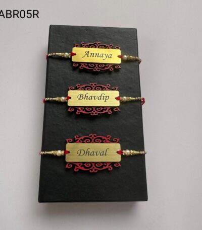 Personalized brushed gold name plate Rakhi with decorative designer base, pearl bead accents, and traditional red thread for Raksha Bandhan.
