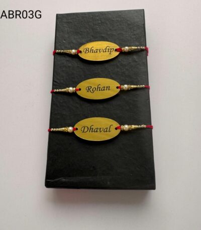 Personalized oval name plate Rakhi available in gold and silver finish with custom engraving, pearl beads, and traditional red thread.