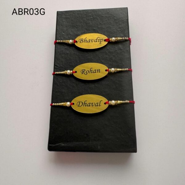 Personalized oval name plate Rakhi available in gold and silver finish with custom engraving, pearl beads, and traditional red thread.