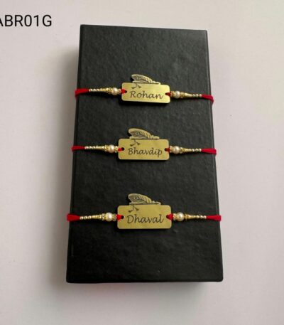 Personalized feather name plate Rakhi available in gold and silver finish with custom engraving, pearl beads, and traditional red thread.
